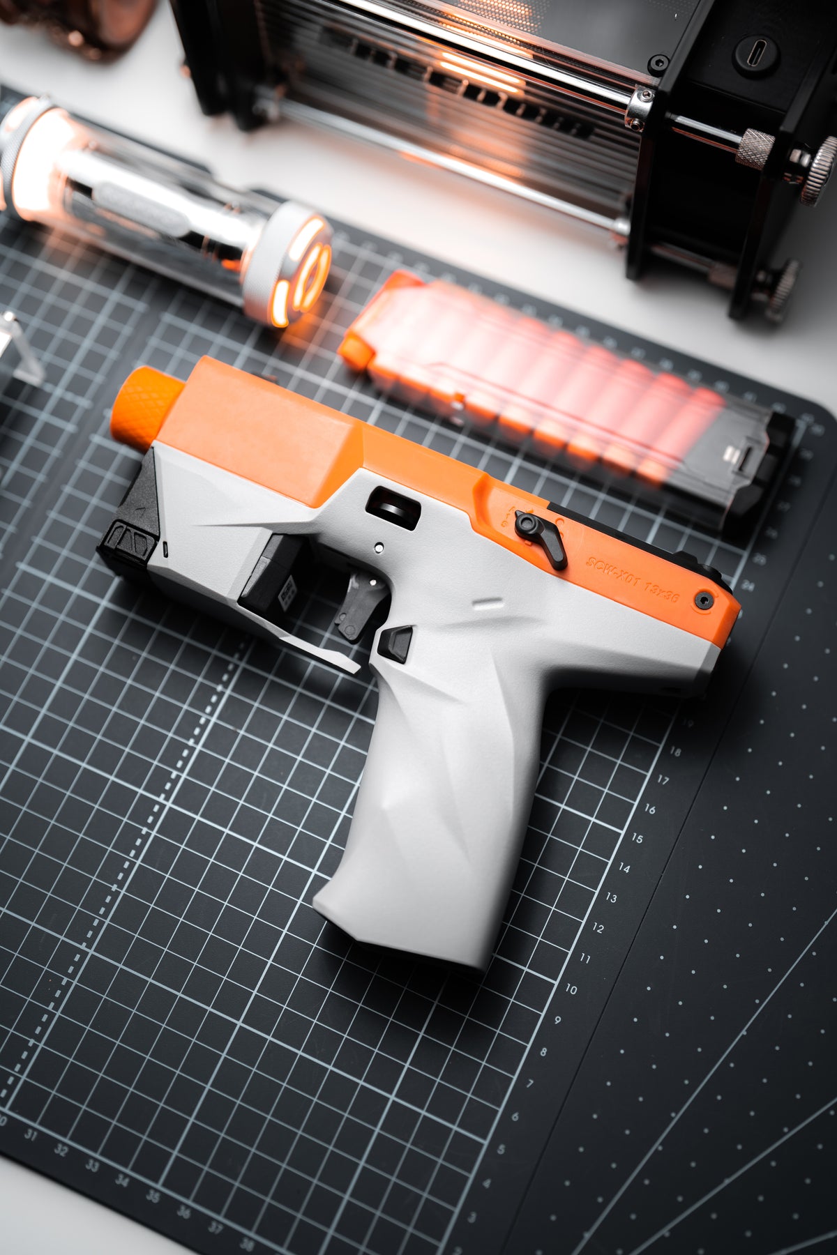 ATROX orange and gray foam dart blaster with clear magazine on a workbench