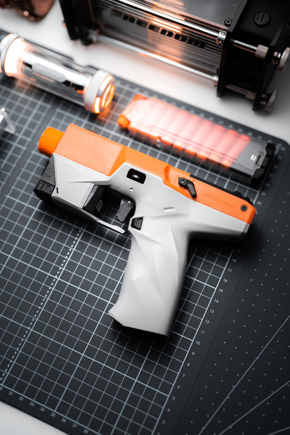ATROX orange and gray foam dart blaster with clear magazine on a workbench